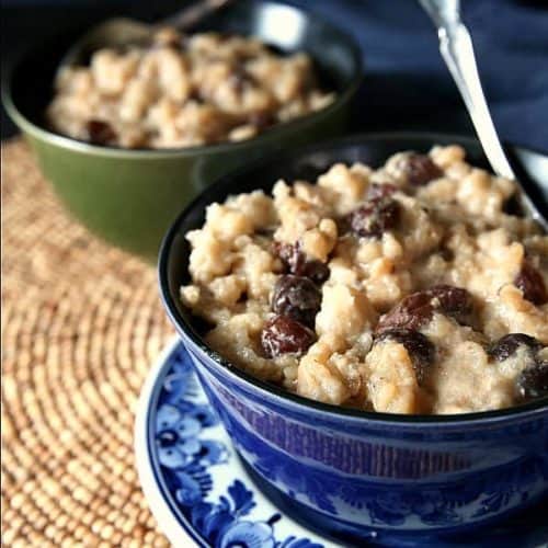 Up close cropped photo of creamy rice pudding filled with raisins with a spoon in it.