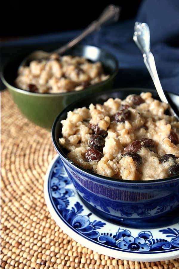 Up close cropped photo of creamy rice pudding filled with raisins with a spoon in it.