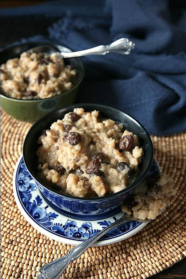 Creamy Rice Pudding is viewed from overhead angle and fills a bowl with a spoonful on the side.