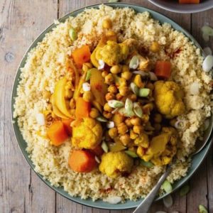 Overhead view of North African food including cauliflower, carrots and chickpeas featured in a square picture.