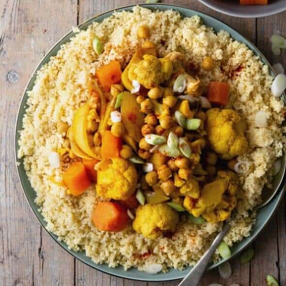 Overhead view of North African food including cauliflower, carrots and chickpeas featured in a square picture.