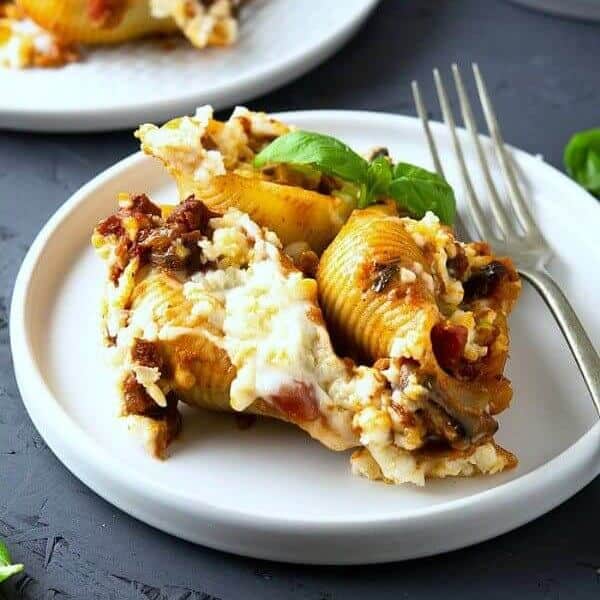 Vegan Stuffed Jumbo Shells are on a while plate with a fork on the right.