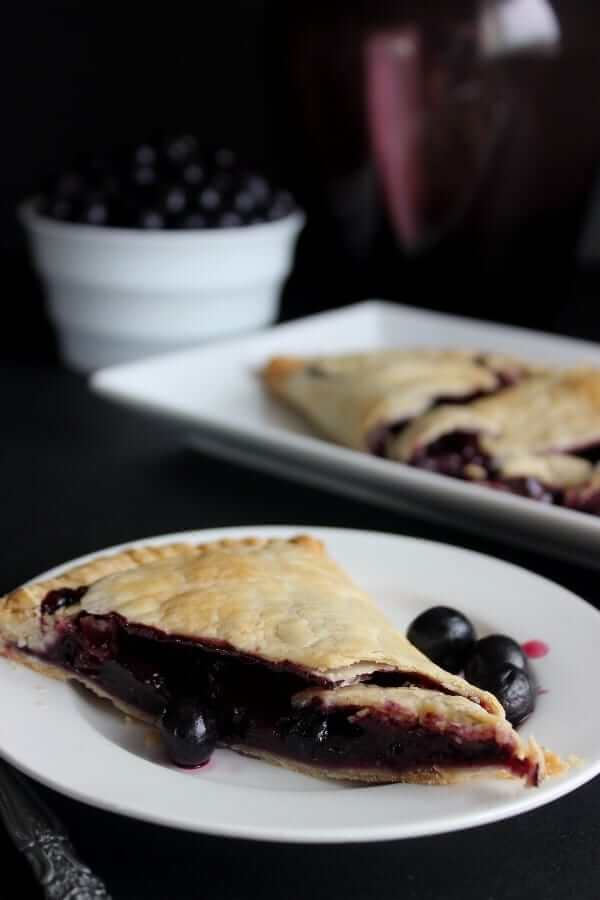 Side view of a slice of pie on a white plate with the remaining slices behind.