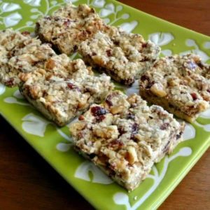 Angled front view photo and close-up up healthy snack bars cut into squares and showing cranberries and dates.