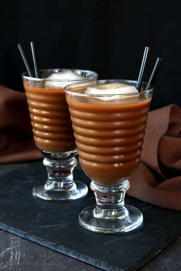 Two tall glasses with iced filled with iced chocolate coffee.
