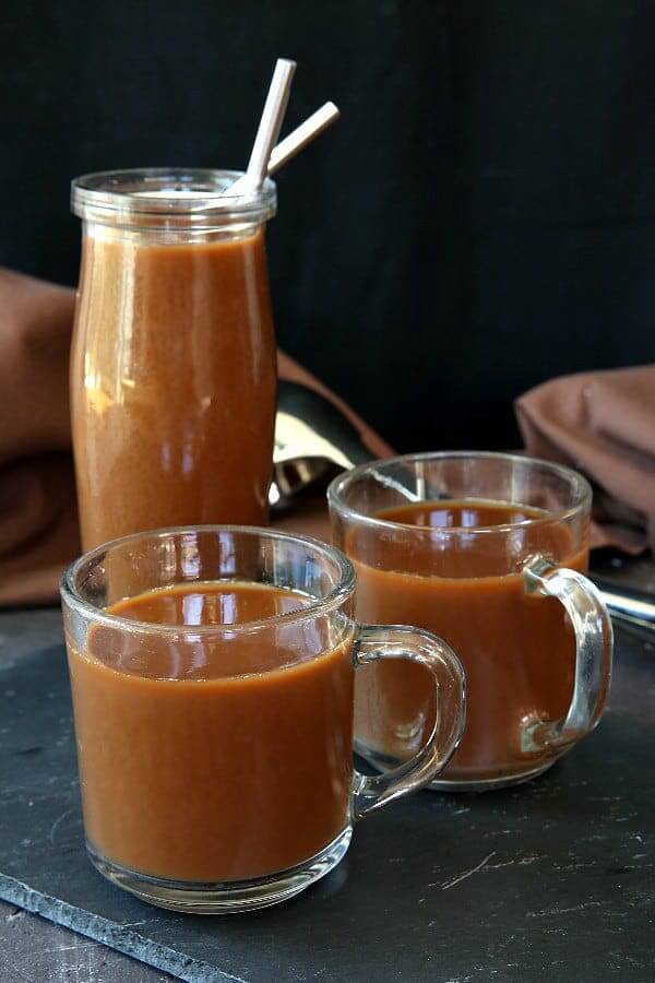 Two mugs full of mocha coffee with an iced coffee mocha behind.