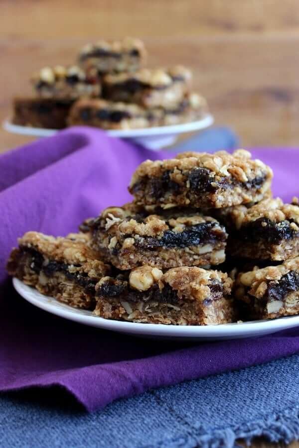 Close-up photo of square cut bars with a rich fruit filling in the center of each bar - stacked high.