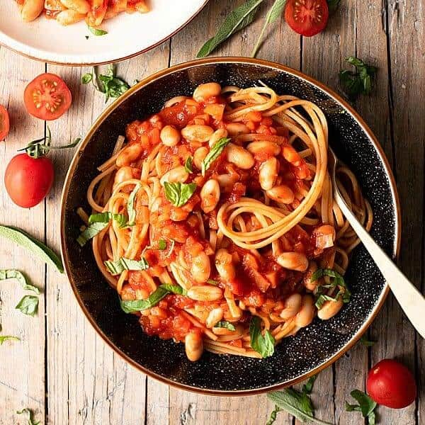 Overhead view of a Pottery bowl filled with pasta and beans and is being scooped up by a fork.