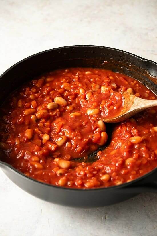 A tilted skillet with fresh ingredients stirred together for Tuscan Pasta and Beans, no pasta yet.