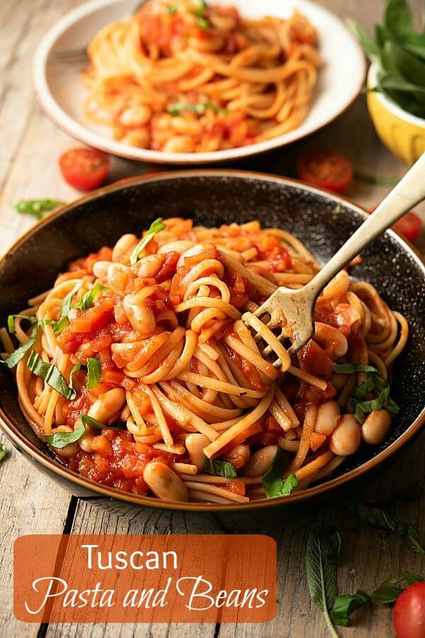 Pottery bowl is filled with pasta and beans and is being twirled on a fork with the recipe title printed on photo.