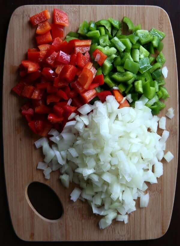 A beautiful big pile of green and red bell pepper along with white onions, dice perfectly.