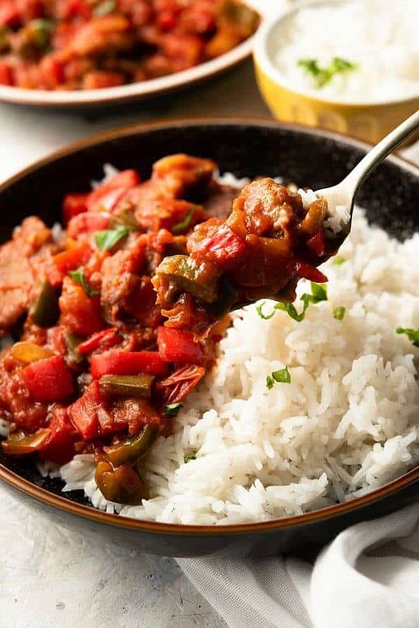 Close-up of a fork full of pepper steak mixture served over rice.