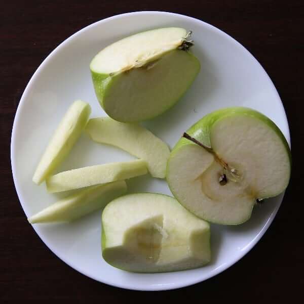 Overhead view of granny smith apples showing the four stages of paring.