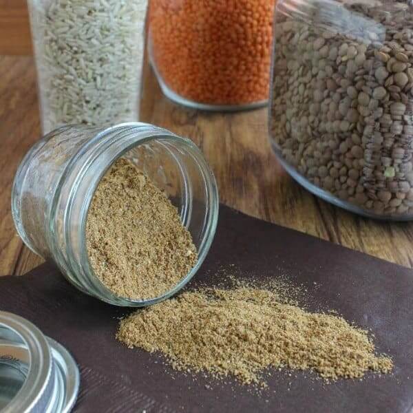 Photo of garam masala spilling out of a half pint far onto a brown napkin.