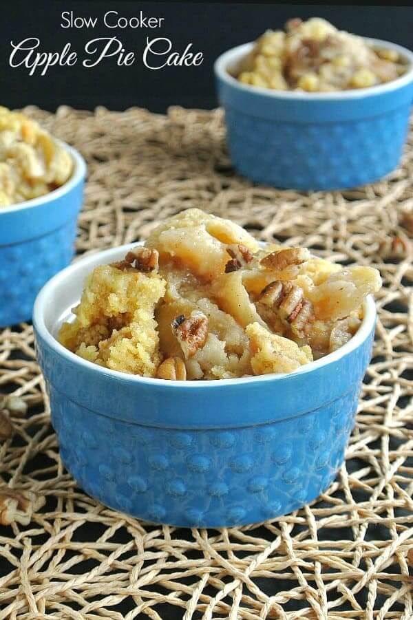 Golden Apple Pie Cake is overflowing in a blue bowl and is sprinkle with chopped pecans.