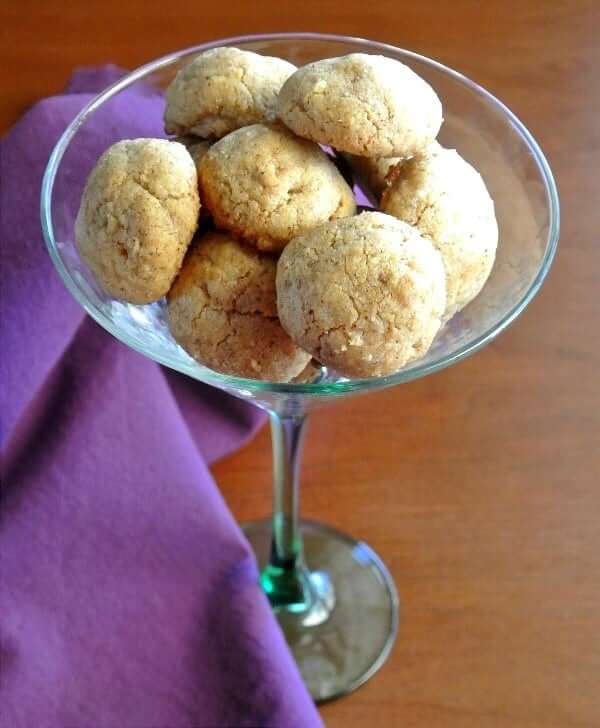 Light almond colored rounded cookies in a martini glass.