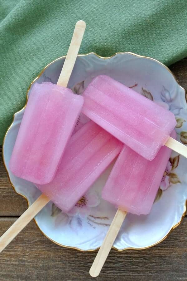 Overhead view of four pink popsicles on an antiqued flower dish.