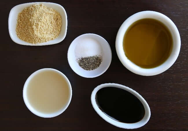 Overhead view of ingredients for Italian dressing plus enhancements all in different shaped white bowls.