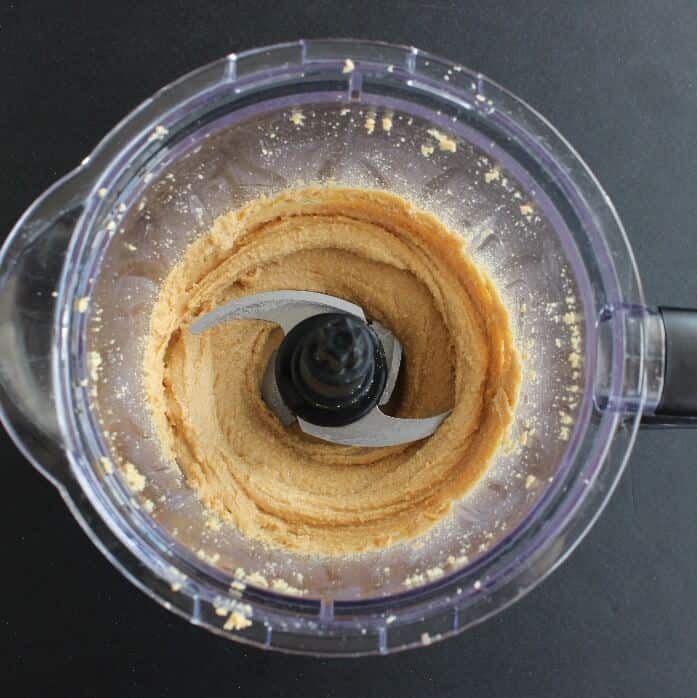An overhead view of peanuts starting to become very creamy in a food processor.
