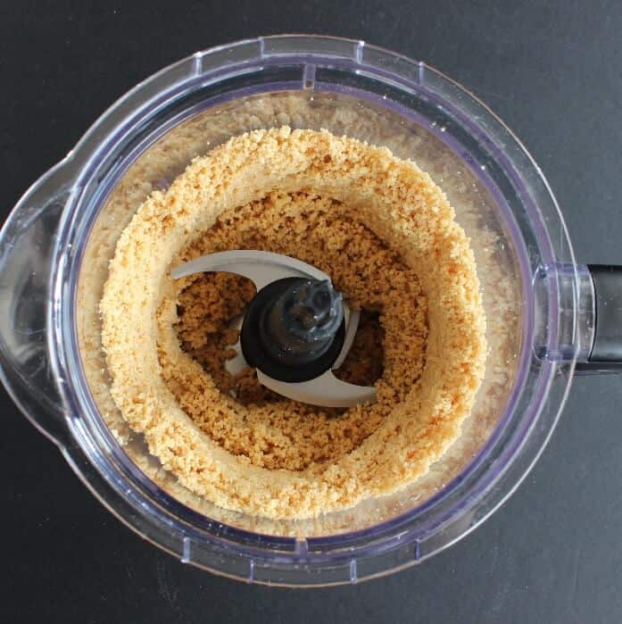 Overhead view of peanuts in a food processor and coarsly ground.