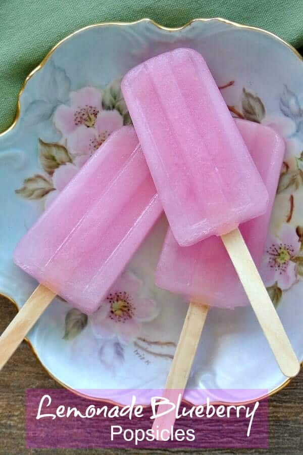Overhead view of three pink popsicles on an antiqued flowered dish.