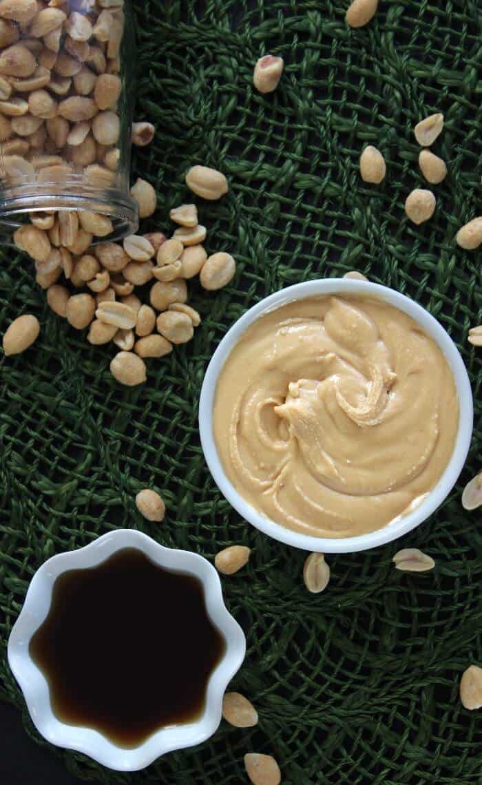 Overhead view of a white bowl with a nut butter and a small white bowl with maple syrup.