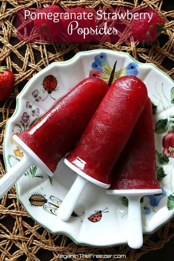 Three pomegranate strawberry popsicles on a retro flower plate with text above.