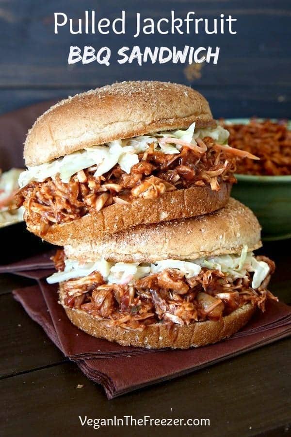 Front view of two big fat BBQ sandwiches stacked on top of each other with green and wood surroundings.