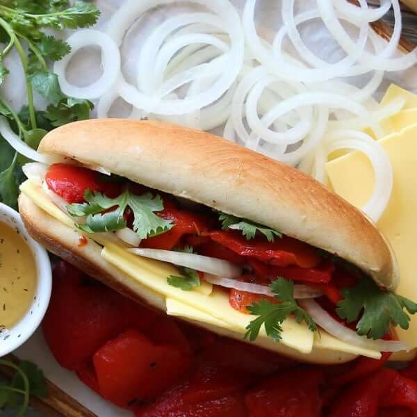 Overhead view of a filled roasted pepper sandwich on a bed of the ingredients.