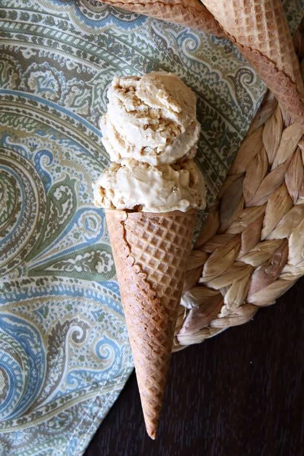 Overhead view of two scoops on a cone laying down on a paisley cloth.