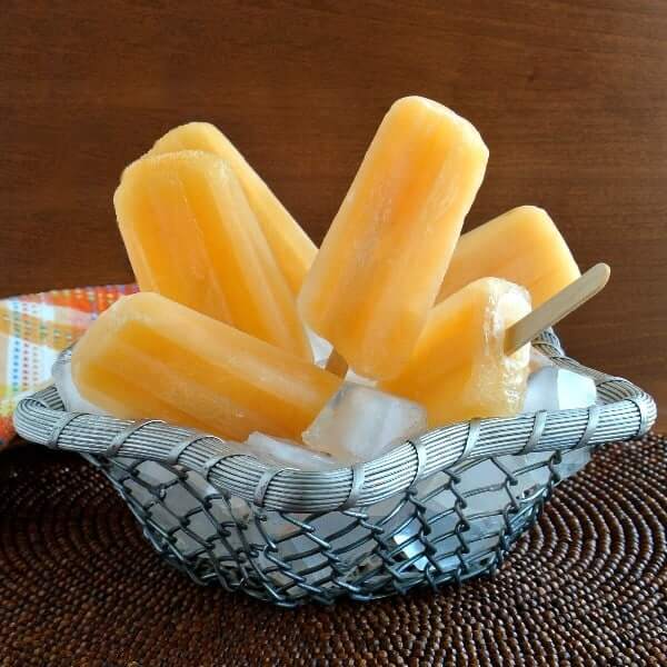 Front picture of real fruit popsicles sticking up out of ice in an openweave silver basket.