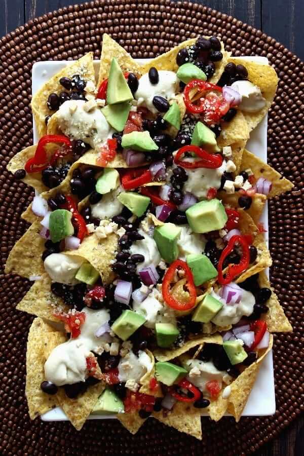 Overhead view of a white rectangle plate loaded with vegan nachos.
