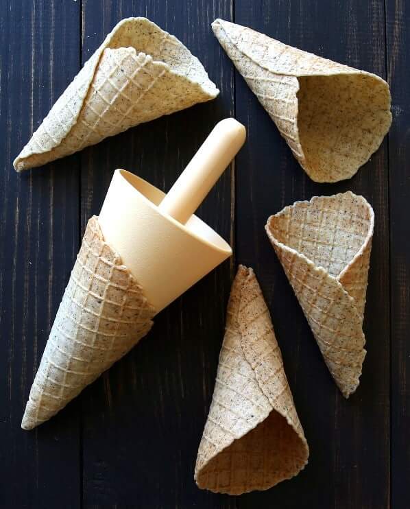 Overhead view of chia waffle cones spread on a picnic table with the cone mold.