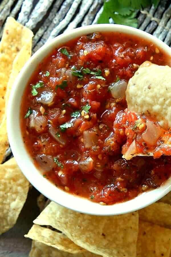 Overhead view of tomato sauce with a chip dipping in for an appetizer.