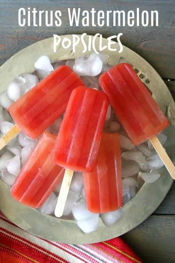 Overhead photo os deep watermelon colored popsicles on ice and a silver platter.