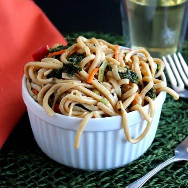 Centered bowl of overflowing pasta salad with carrots and kale.