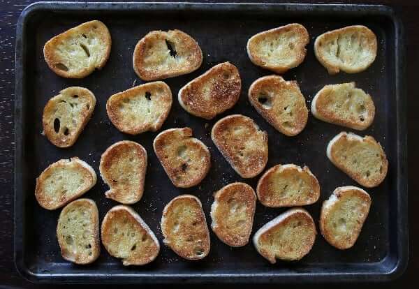 Overhead view of tasted crostini toasts in a baking sheet.