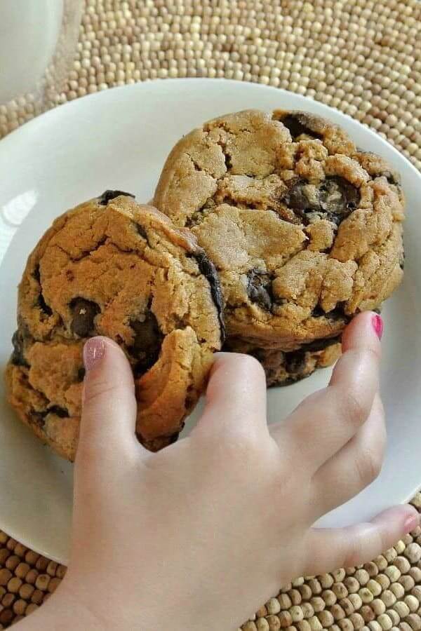 Three giant cookies with one little girls hand picking up the front one.