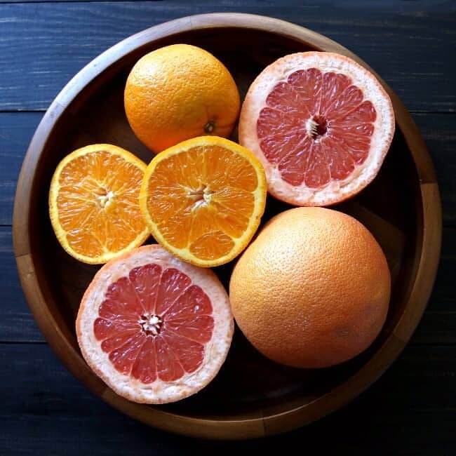 Overhead view of fresh pink grapefruit and oranges with some cut in half.