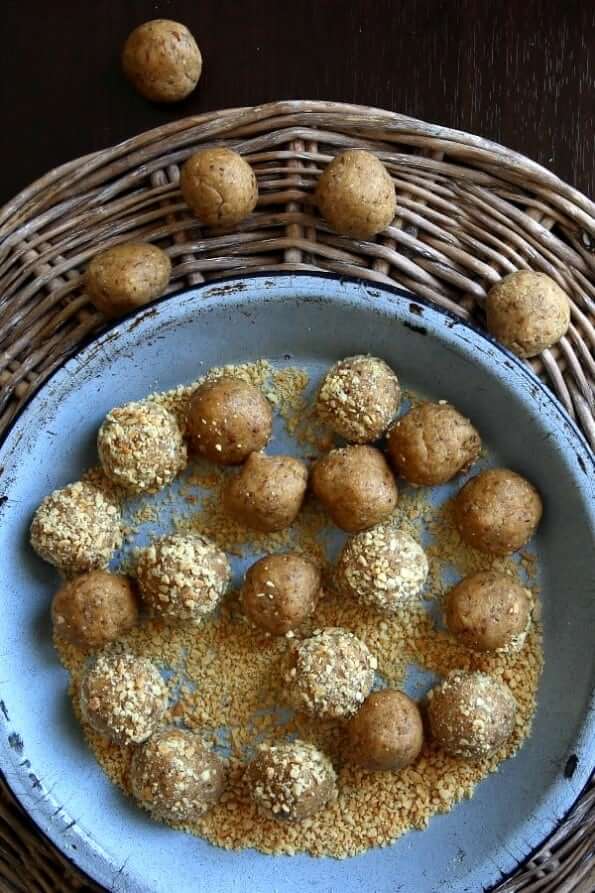 Overhead photo of no bake balls being rolled in ground peanuts.