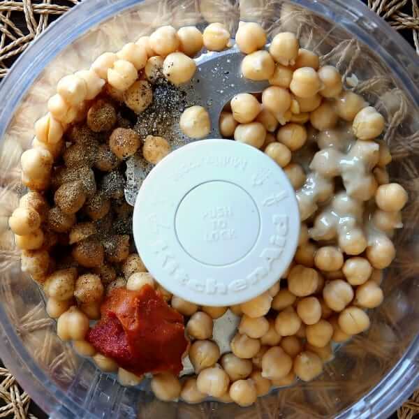 Overhead ohoto of chickpeas and the remaining ingredients for spicy hummus in a food processor.