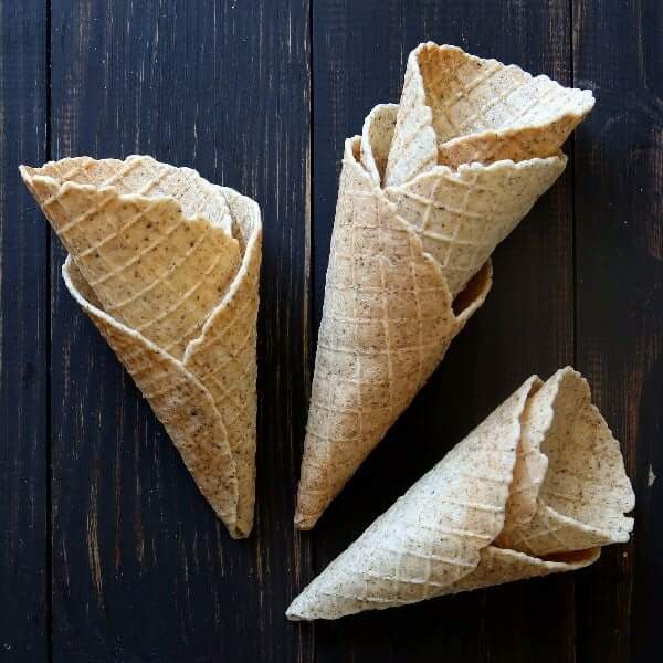 Overhead photo of 7 waffle cones stacked and scattered on a picnic table.