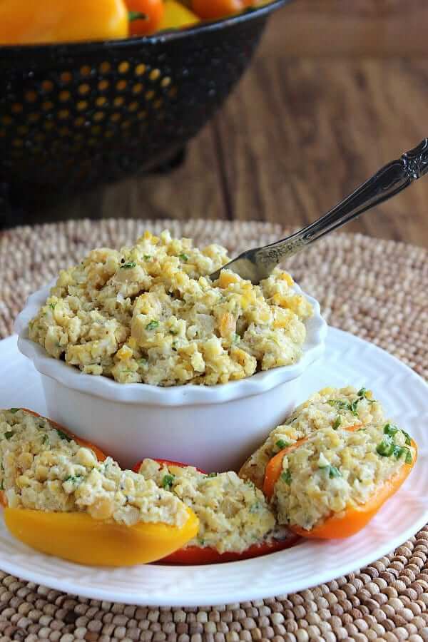 Close up view of stuffed colorful vegetables in front of a bowl of chickpea stuffing.