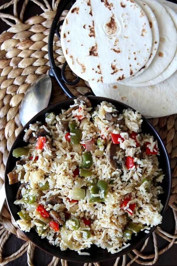 Above photo of bowl of colorful veggies mixed in with rice in a chocolate bowl for one of the 27 vegan Mexican style recipes in this roundup.