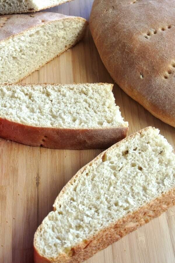 Multiple slices of dairy free bread laying across a wooden cutting board.