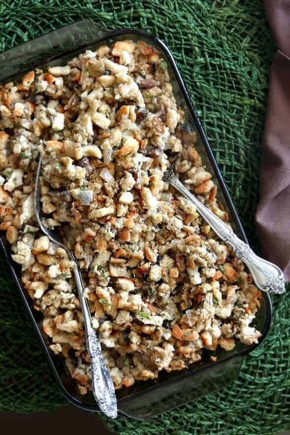 Overhead casserole dish full of stuffing and two large serving spoons.