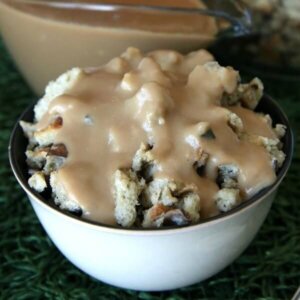 A bowl full of mushroom stuffing is covered with creamy vegan brown gravy on a green mat.