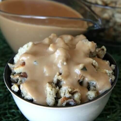 A bowl full of mushroom stuffing is covered with creamy vegan brown gravy.