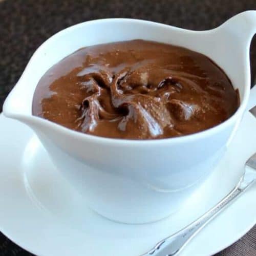 Healthy Homemade Nutella is filling a white creamer on a tray with a spreading knife on the side.