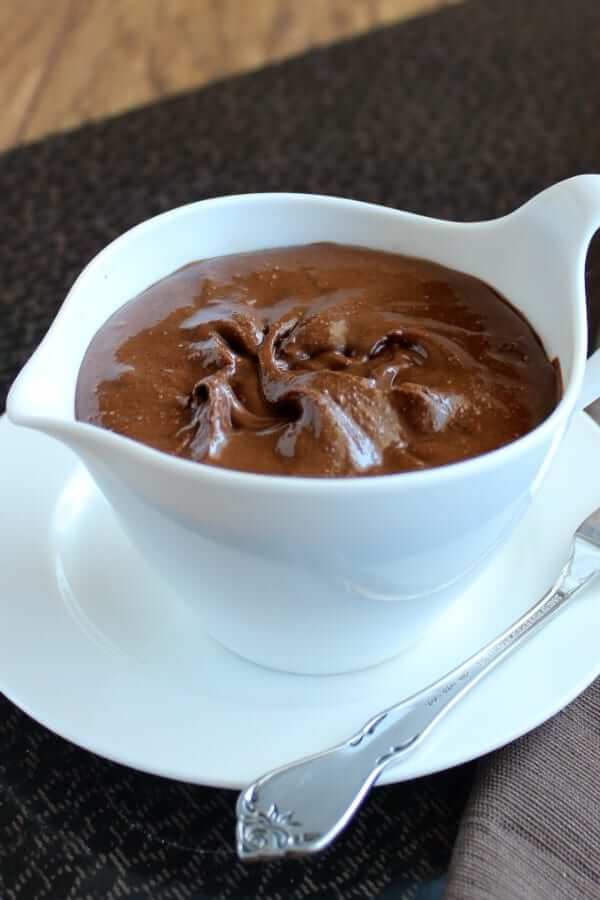 Healthy Homemade Nutella is filling a white creamer on a tray with a spreading knife on the side.